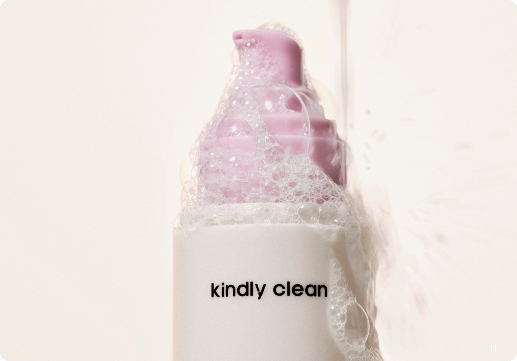 Bottle labeled 'kindly clean' with a pink cap on a light background