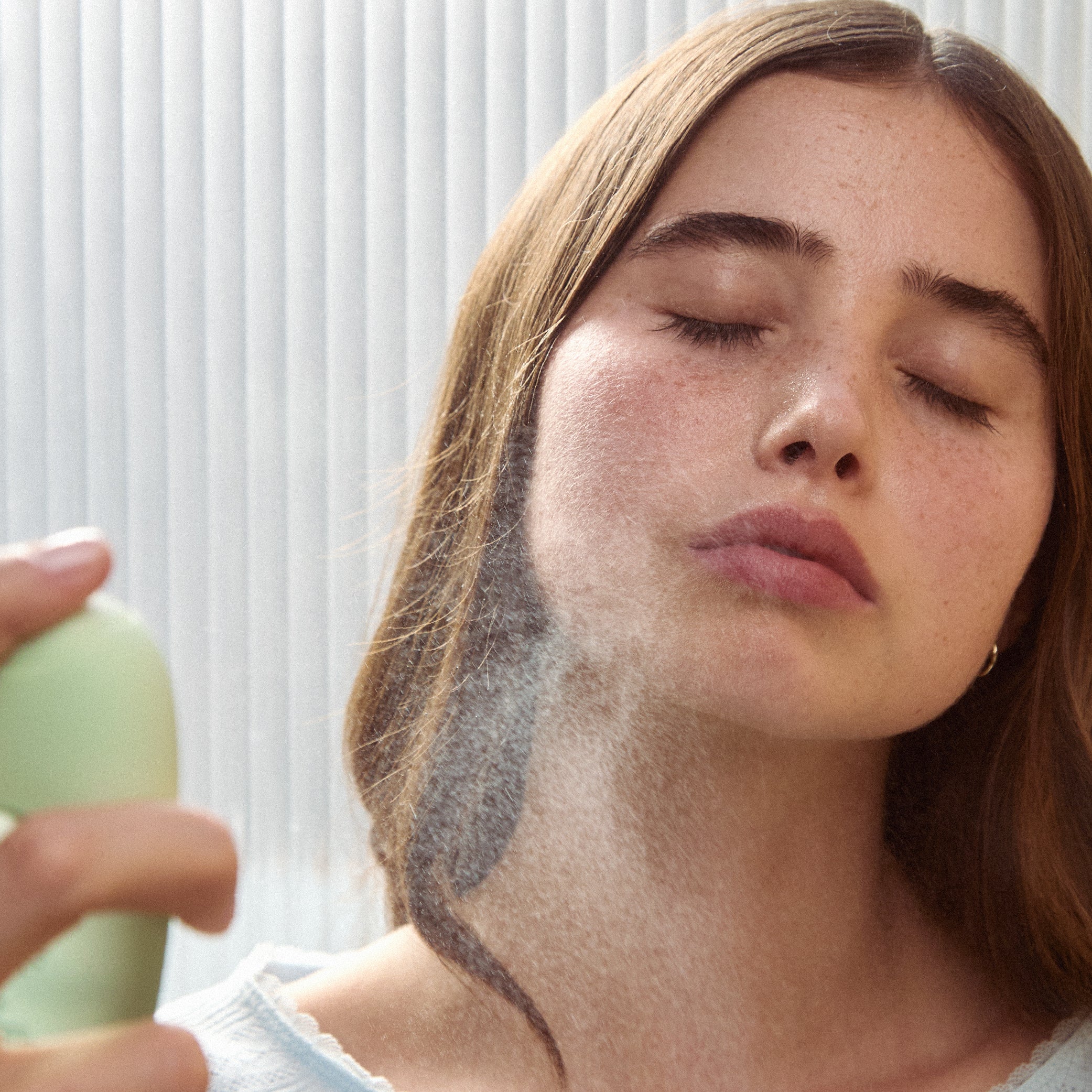 Woman applying Sincerely Yours Hit Refresh to her face with a neutral background