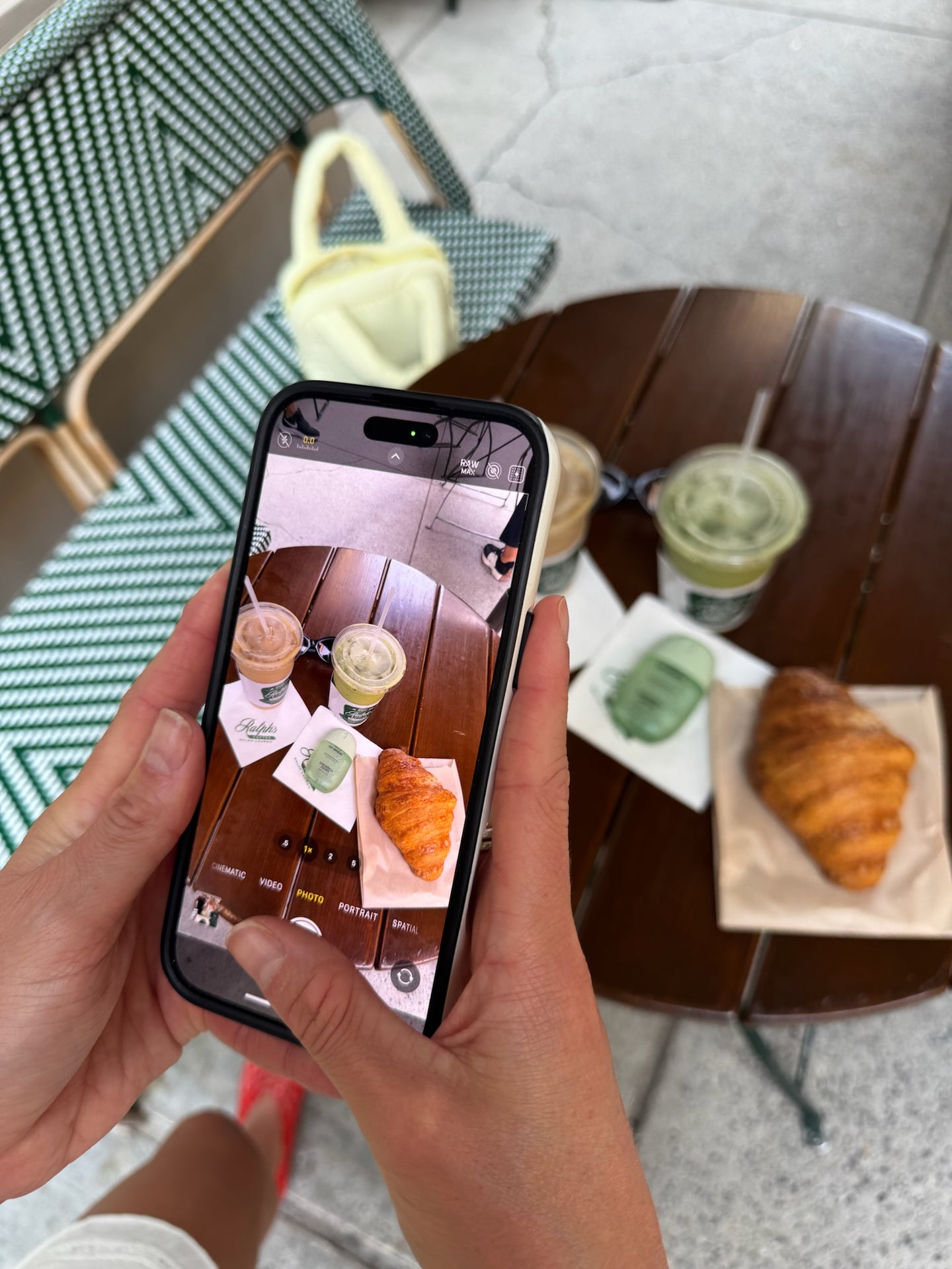 Person holding a phone taking a photo of a table with coffee and pastries.