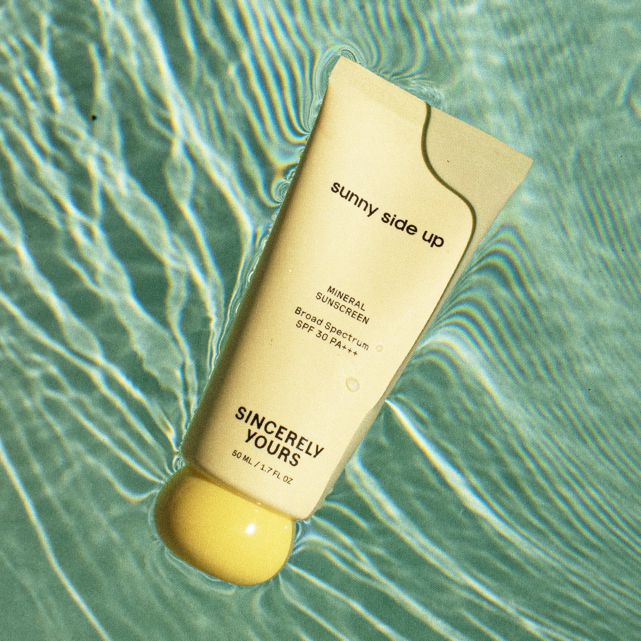 Sunscreen bottle labeled 'sunny side up' on a water surface